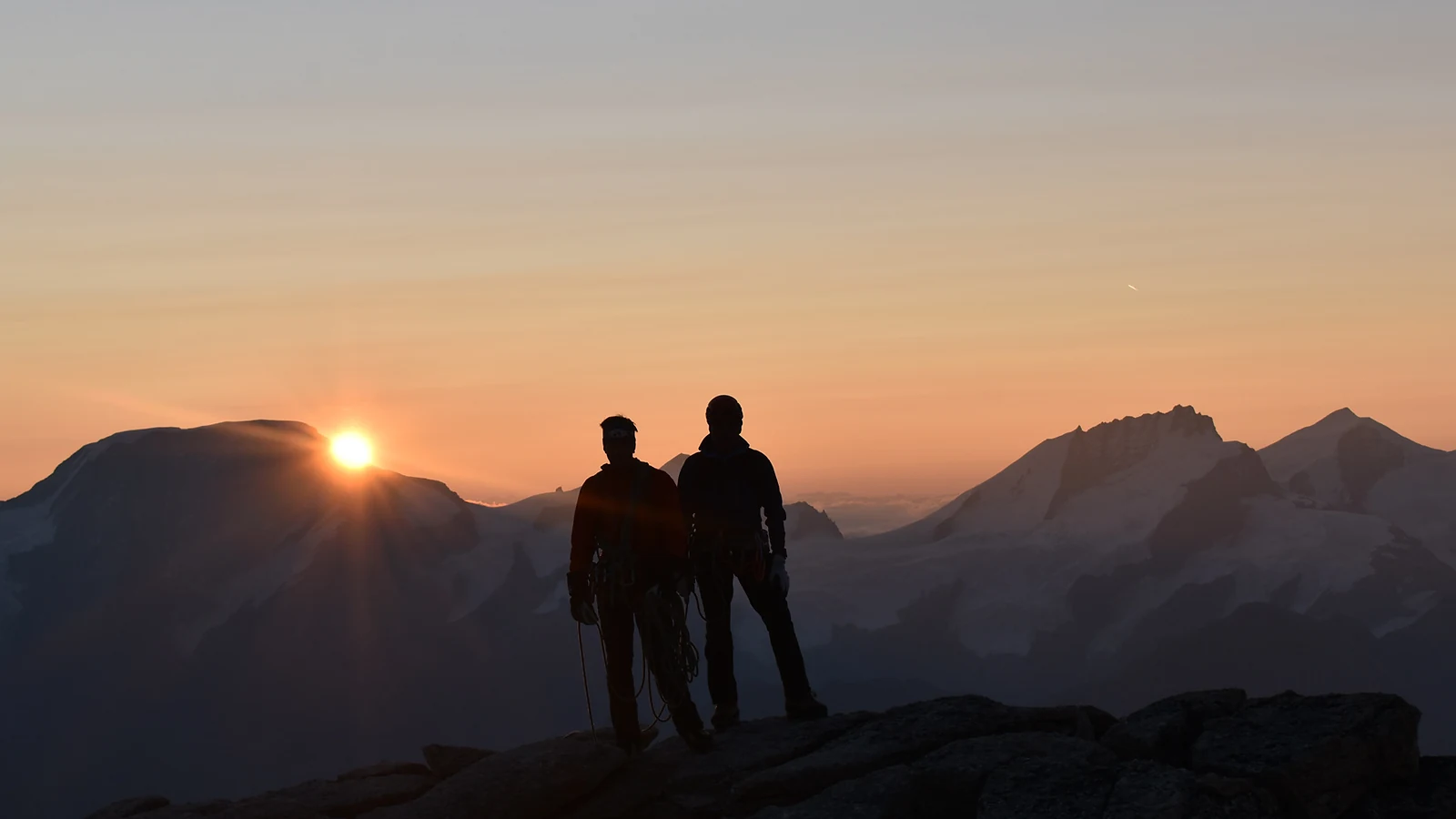Zwei Bergsteiger als Silhouetten bei Sonnenaufgang am Gabelhorn