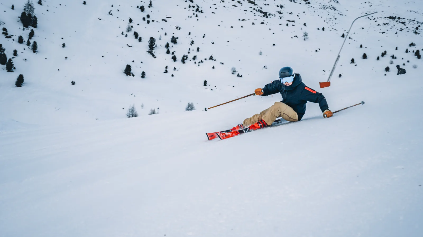 Skifahrer in einer Carving-Kurve mit Skilift im Hintergrund