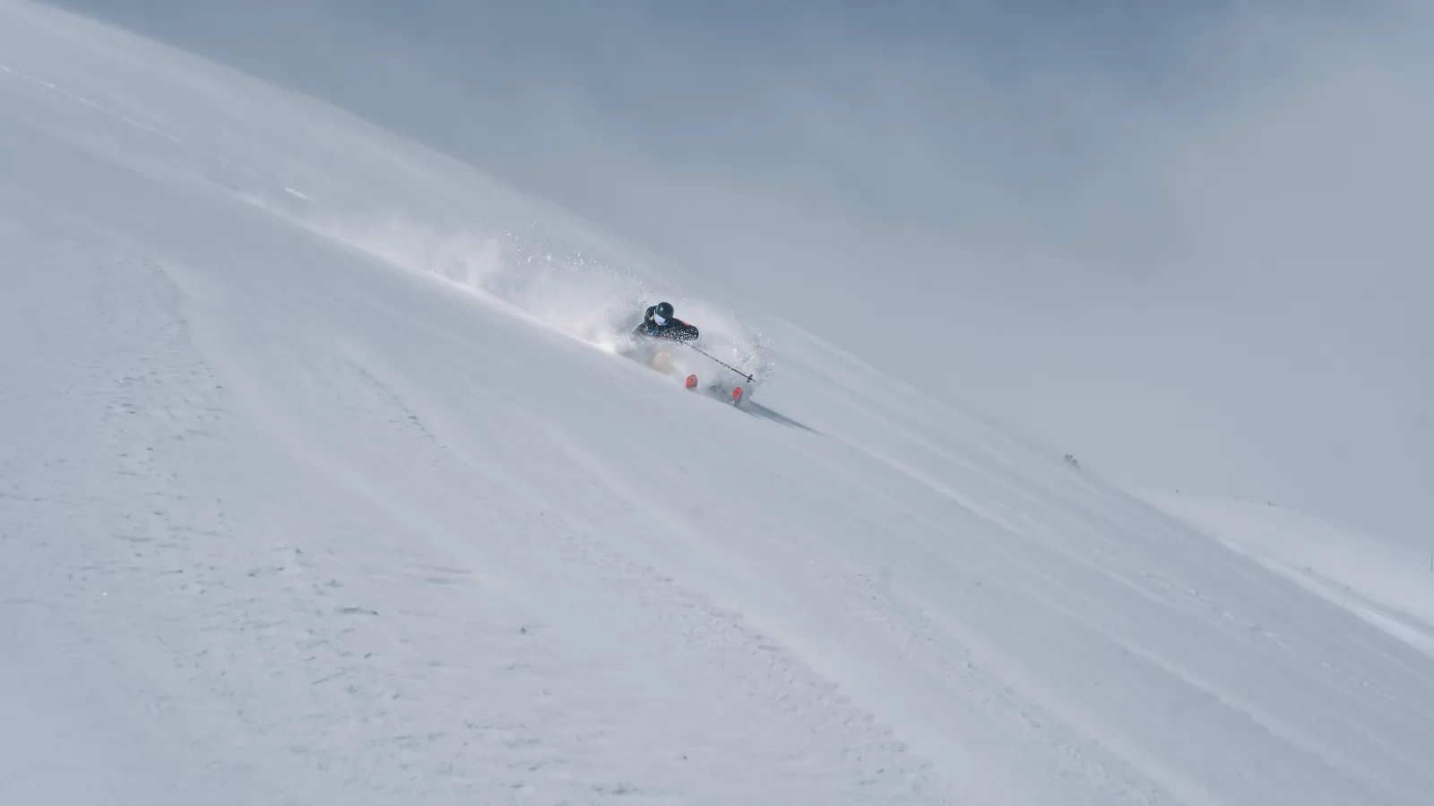 Skifahrer bei einer steilen Abfahrt im Pulverschnee