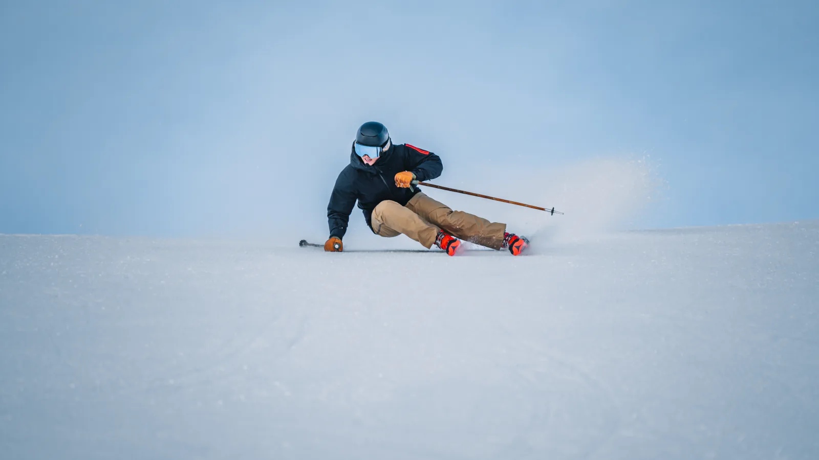 Skifahrer in einer tiefen Carving-Kurve vor blauem Himmel